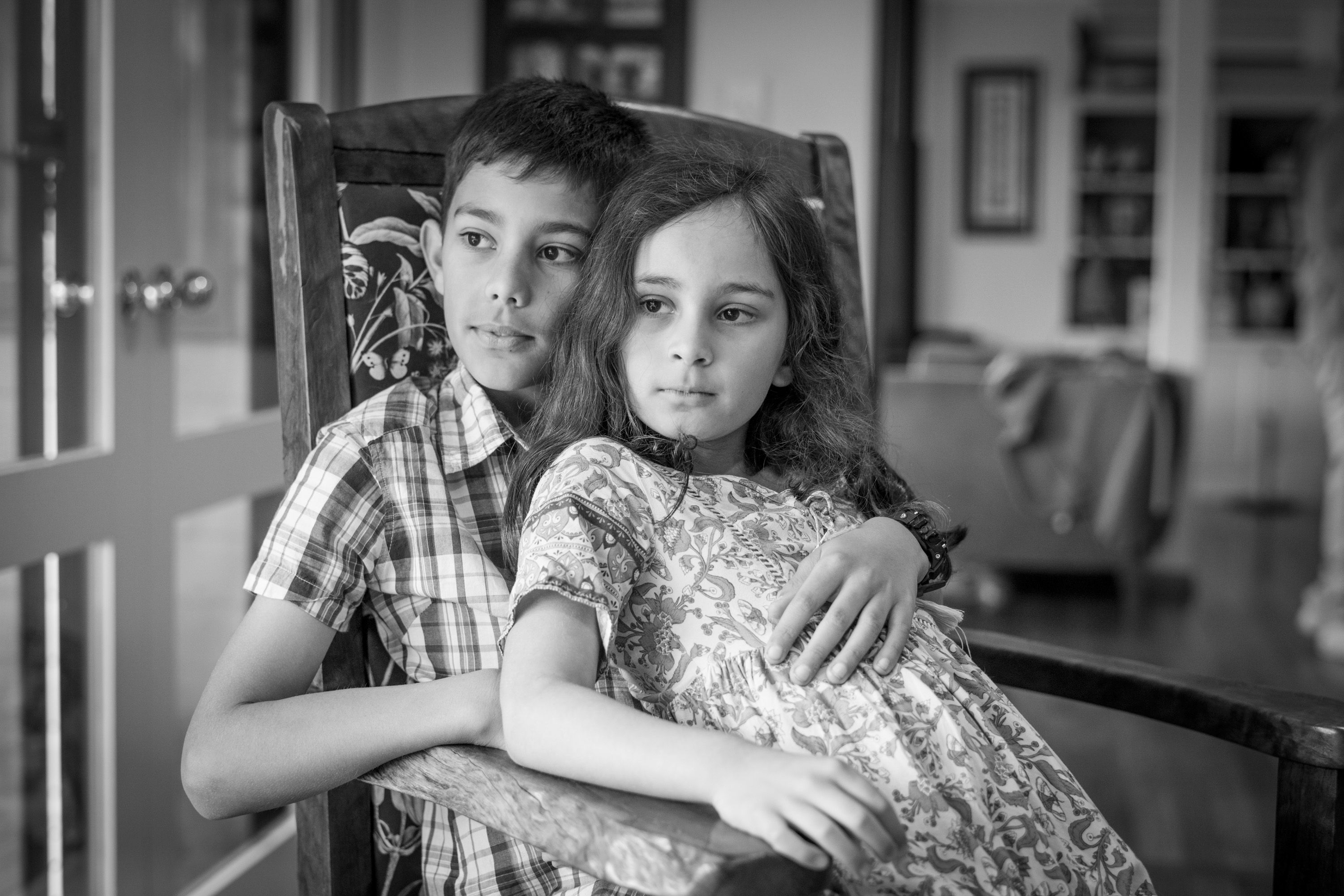 Two sisters cuddled together on a couch, in black and white