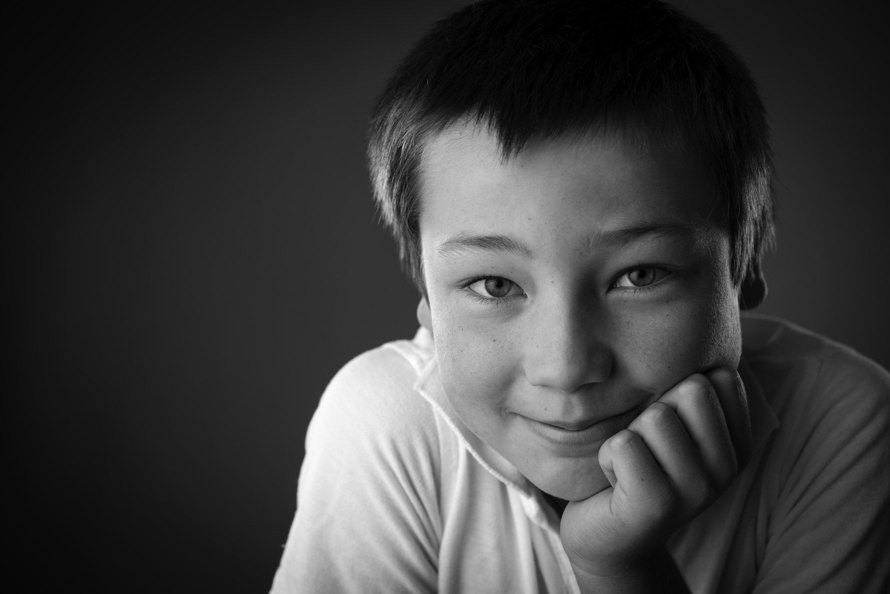 A boy resting his chin on his hand, in black and white