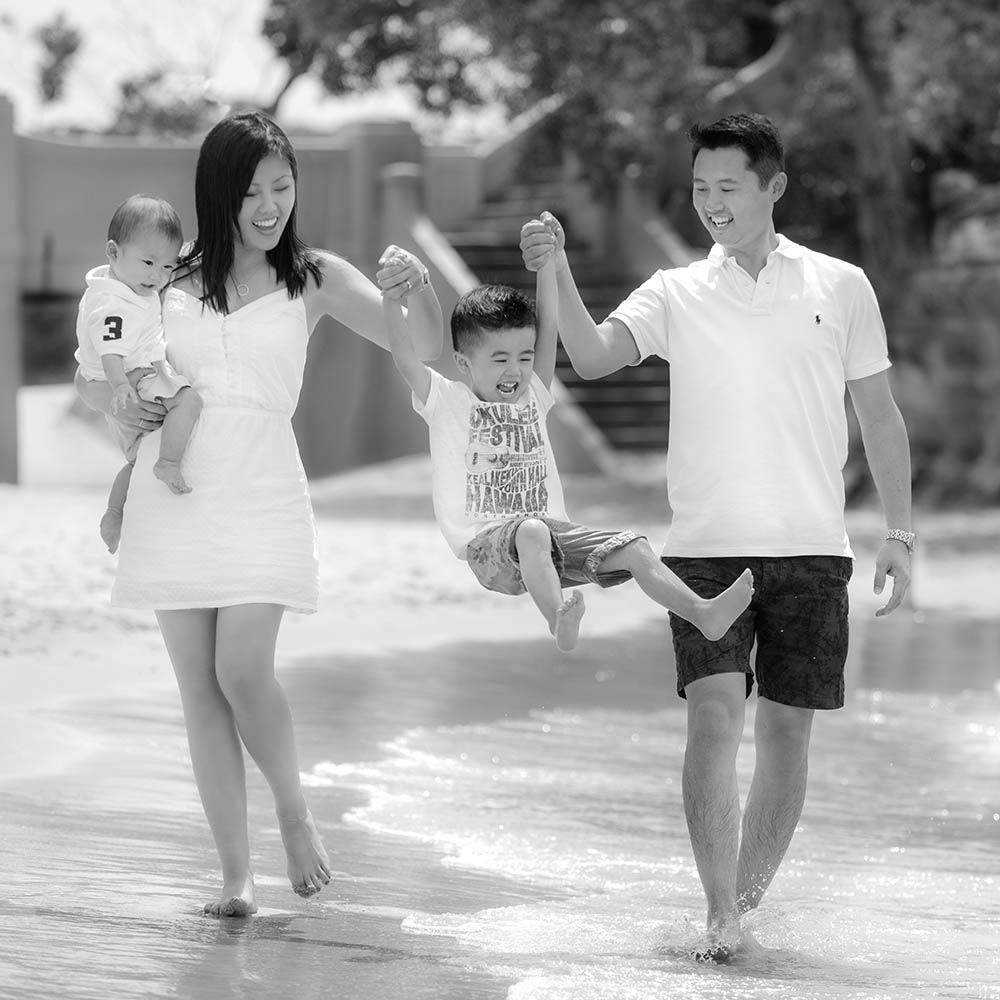 Parents swinging their small son between them at the beach