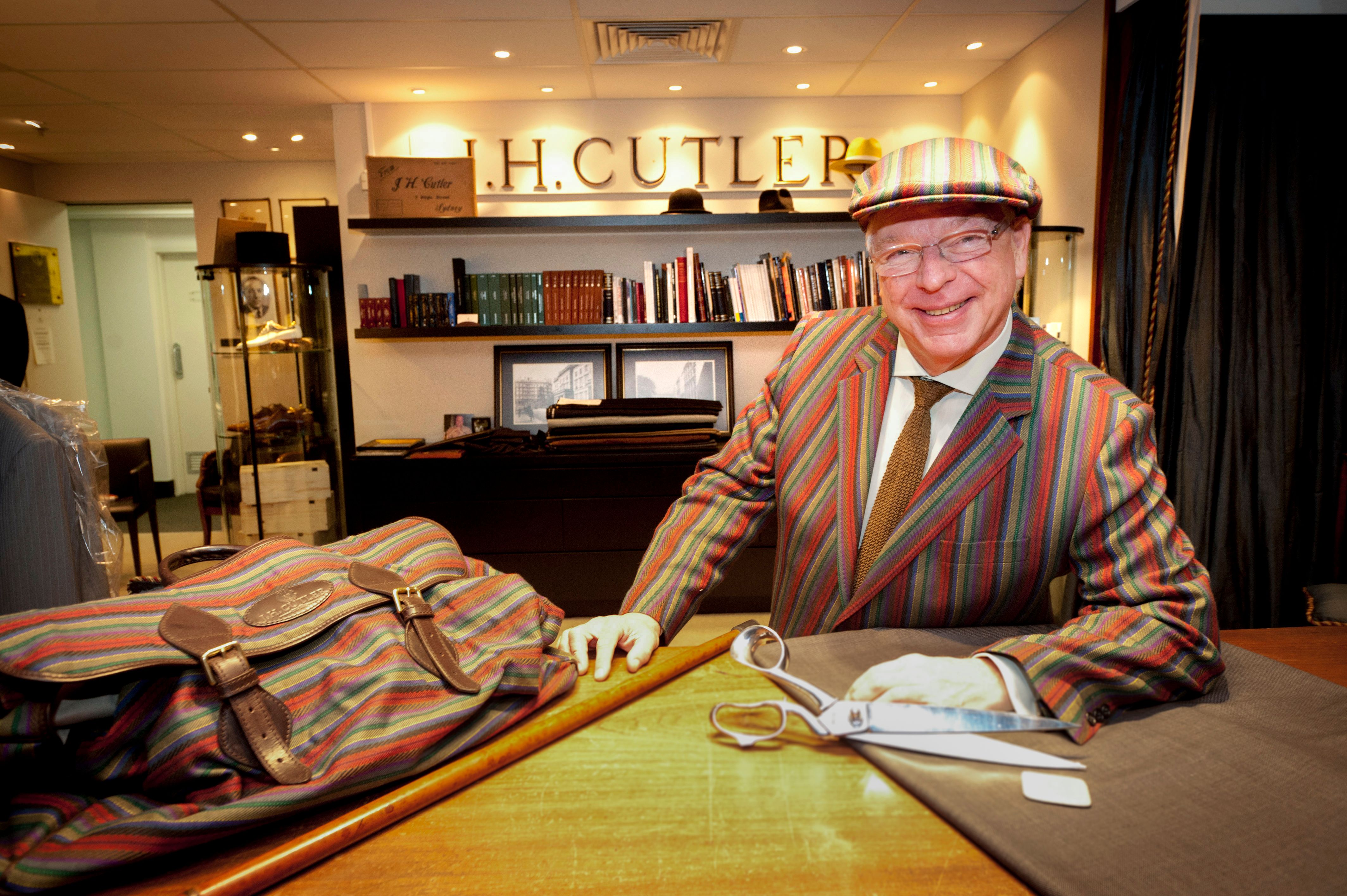 A tailor in a striped jacket at the counter of his shop