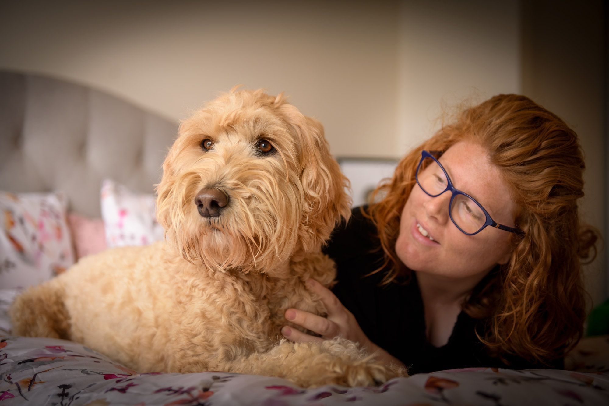 A woman lying beside her golden doodle at home